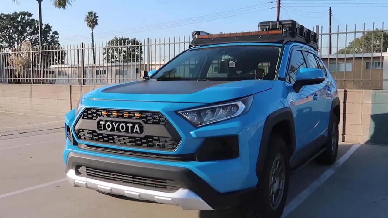 A blue RAV4 Adventure with a Prinsu roof rack loaded with gear