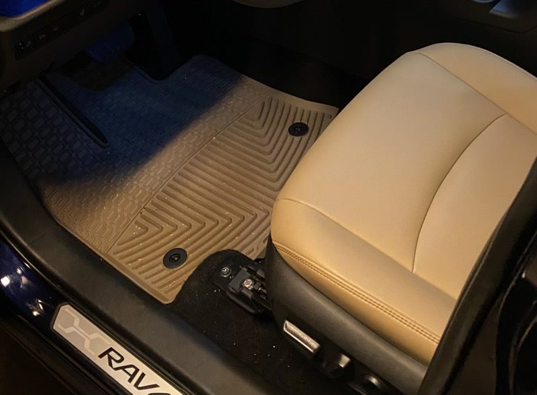 A tan WeatherTech FloorLiner in the driver's footwell of a RAV4 with a caramel interior