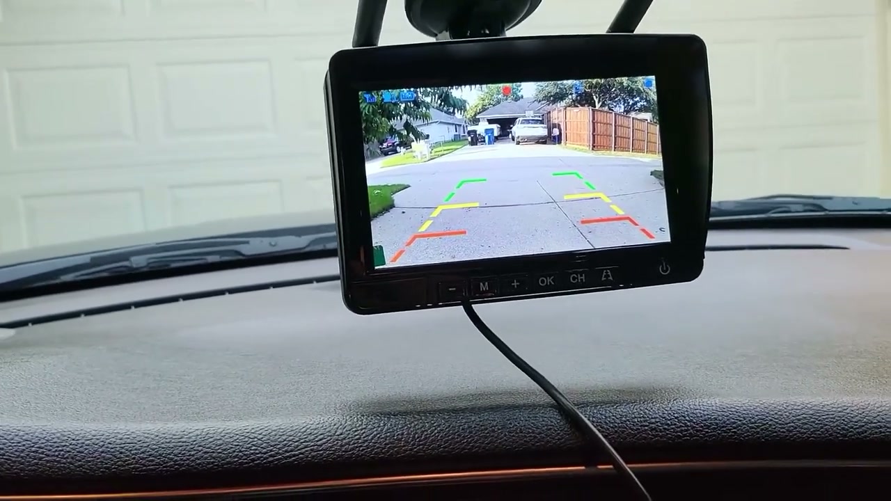 The DVKNM 7-inch monitor on a car dashboard showing the rear camera's live view