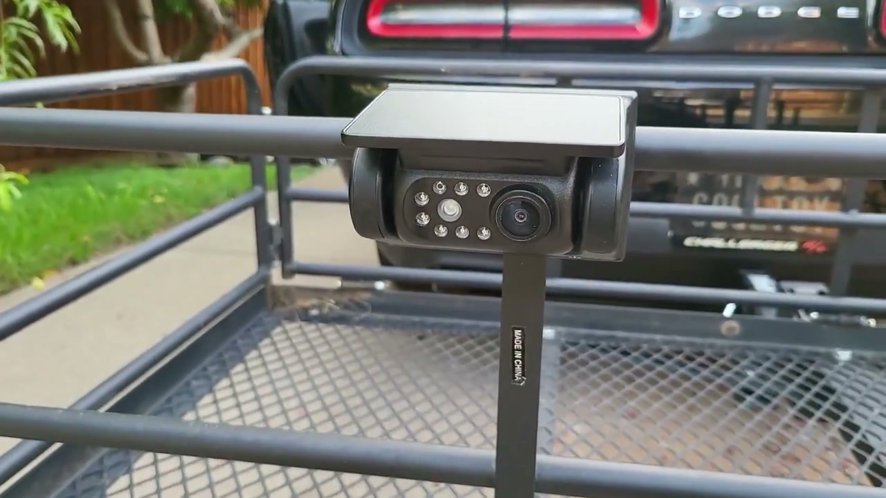 A DVKNM solar wireless camera clamped to a hitch cargo carrier behind a car