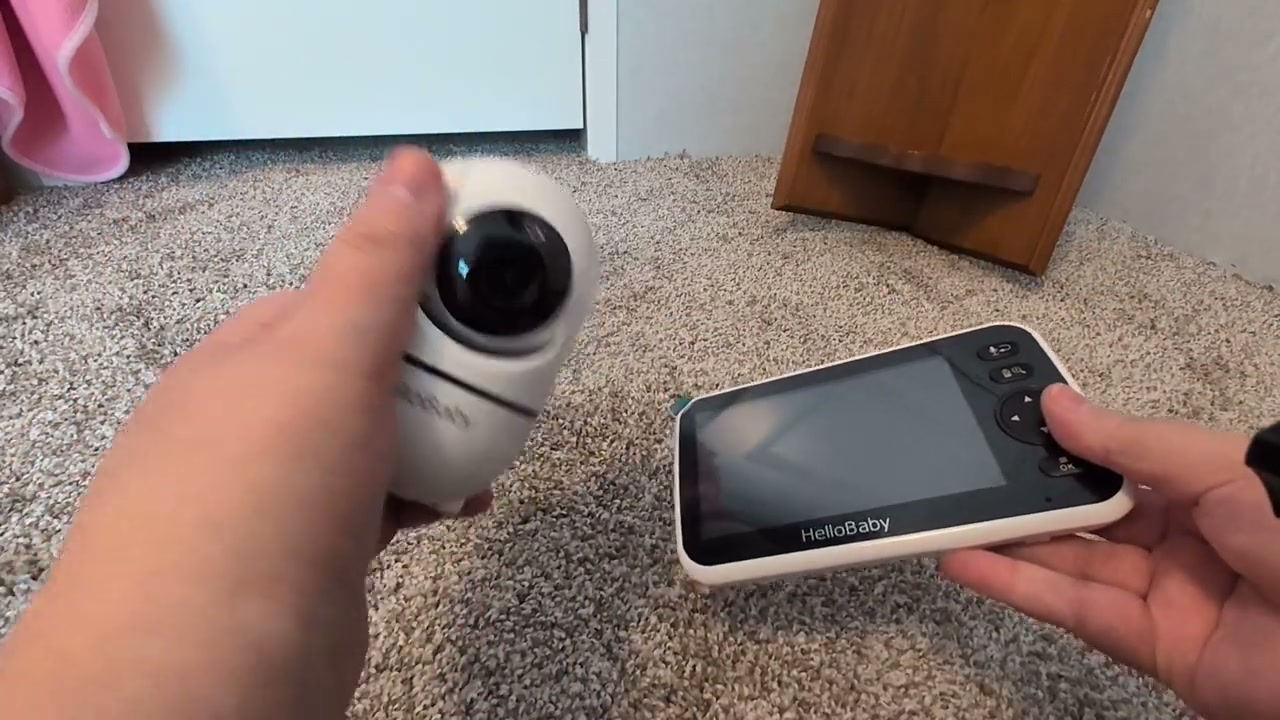 An owner holding the HelloBaby HB6550 camera next to its 5-inch monitor