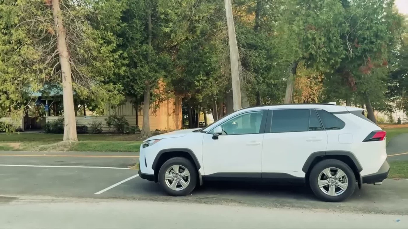A white RAV4 parked by a curb with clear front windows and dark-looking rear windows