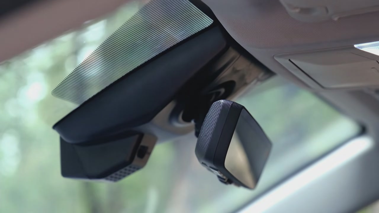 A Fitcamx dash cam housing behind the mirror of a 2019 to 2025 RAV4, looking like a factory part