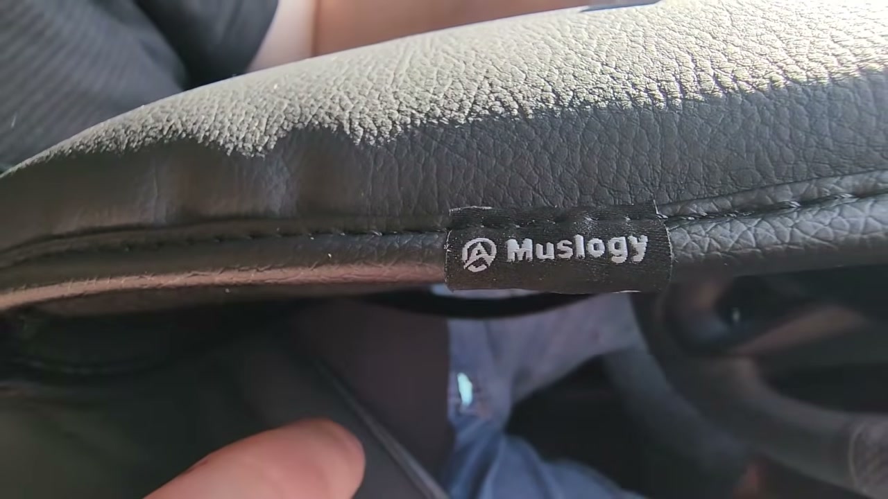 Close-up of a black Muslogy armrest cover with its logo tag, fitted on a RAV4 center console