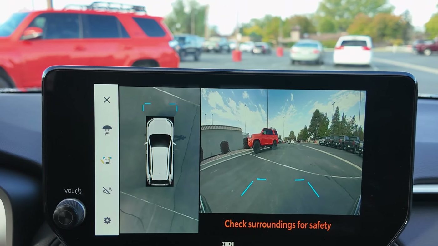 The 360 camera screen on a 2025 RAV4 XSE in Drive, with the top-down view and the front camera, and the A button second from the bottom of the left button strip with a slash through it