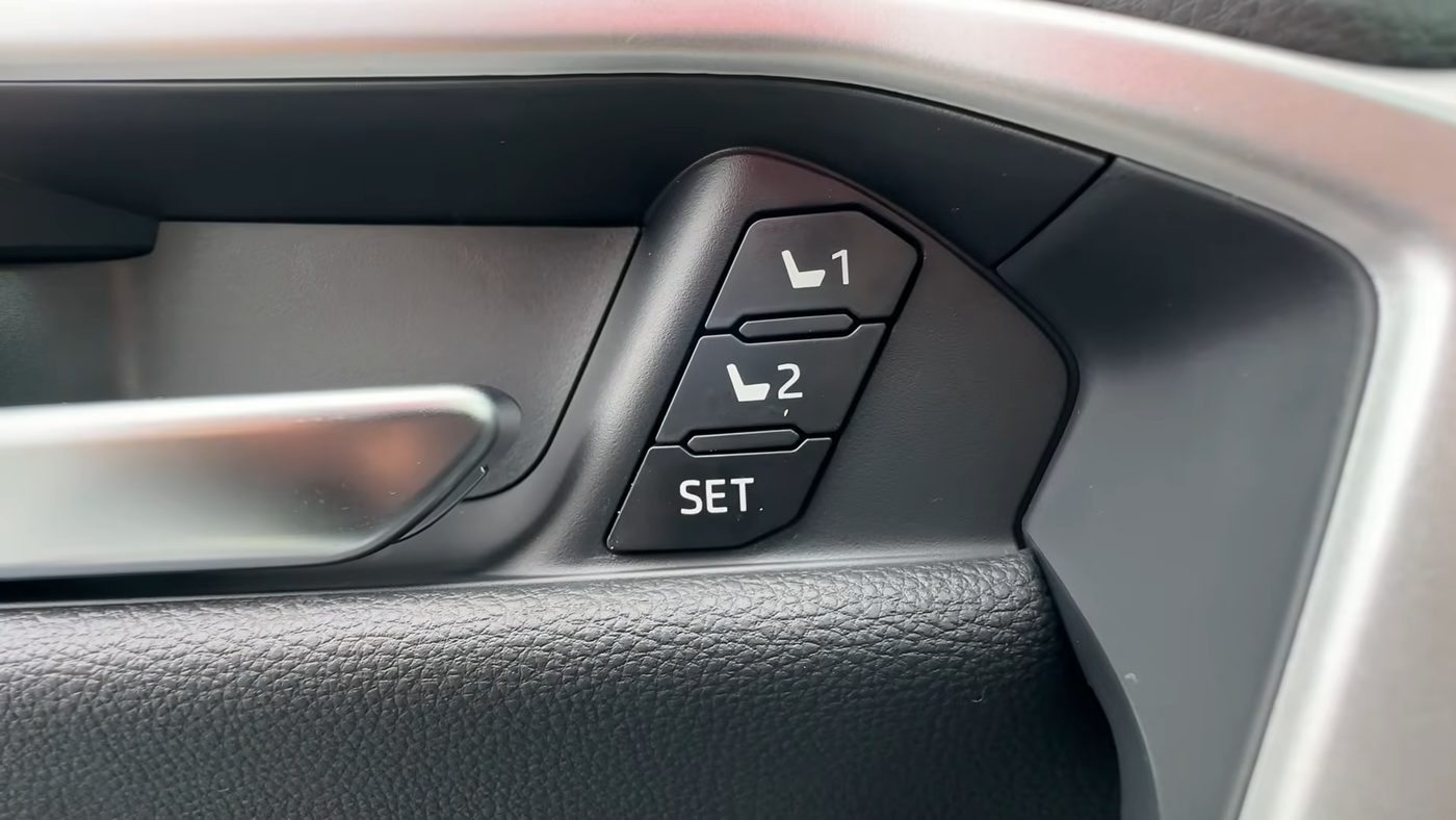 Close-up of the memory seat buttons on the driver's door of a 2023 to 2025 RAV4, with the 1 button on top, the 2 button in the middle and the SET button at the bottom, just to the right of the inside door handle