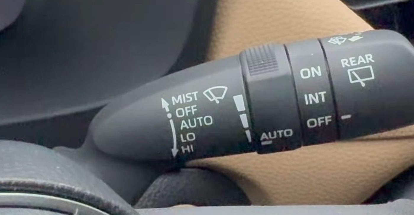 Close-up of the wiper stalk on a 2019 to 2025 RAV4 with rain-sensing wipers, showing MIST, OFF, AUTO, LO and HI printed on the end, the sensitivity ring with its tapered marks behind them, and the rear wiper ring reading ON, INT and OFF