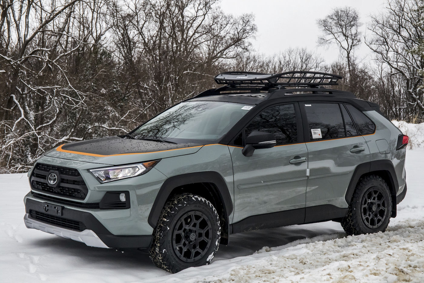 A Lunar Rock 2020 RAV4 Adventure on matte black Black Rhino Overland wheels and all-terrain tires in the snow, with a roof basket