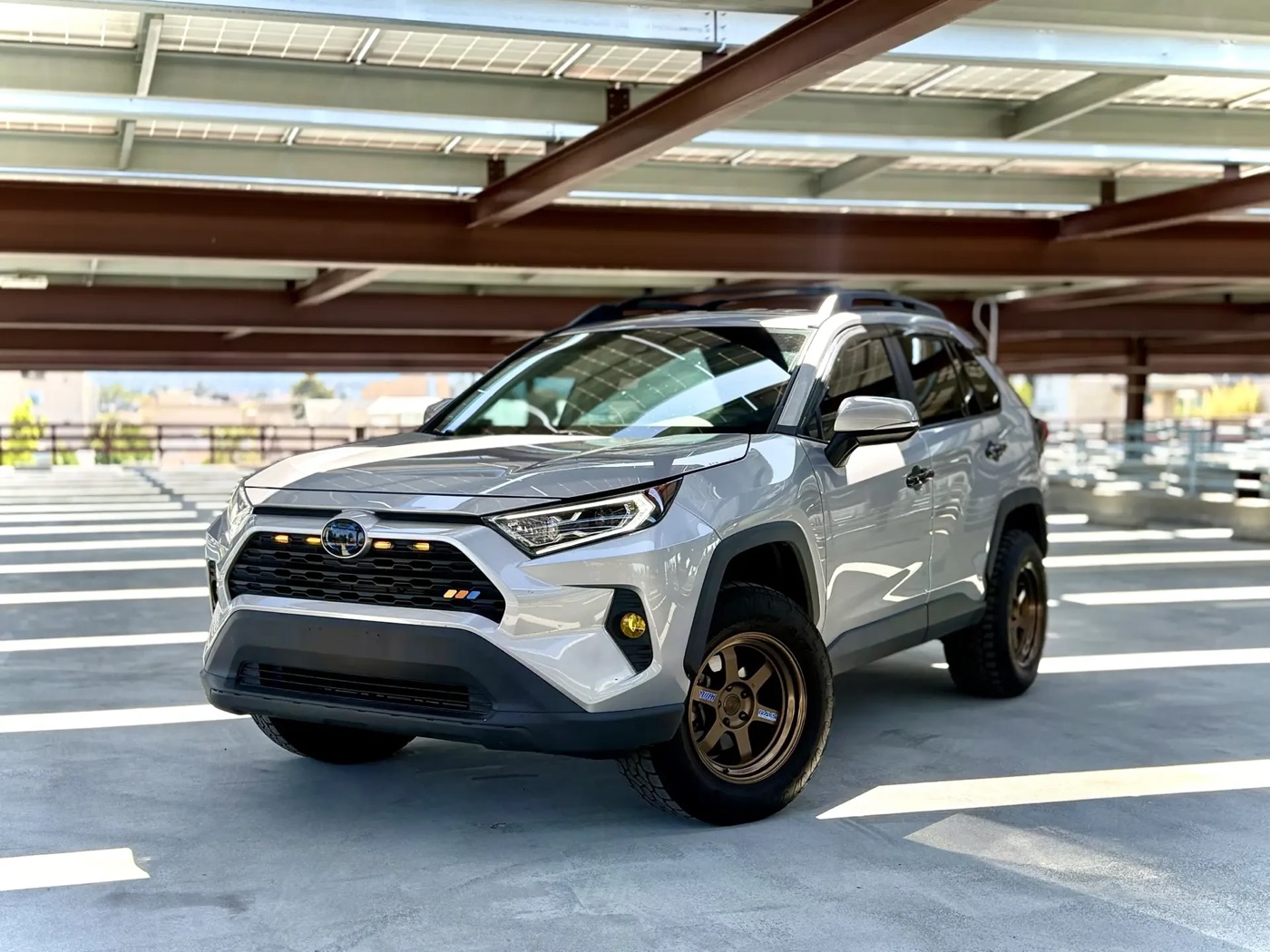 A white RAV4 on bronze Volk TE37V wheels and Toyo Open Country A/T III tires in 265/65R17 with a 1.5-inch lift
