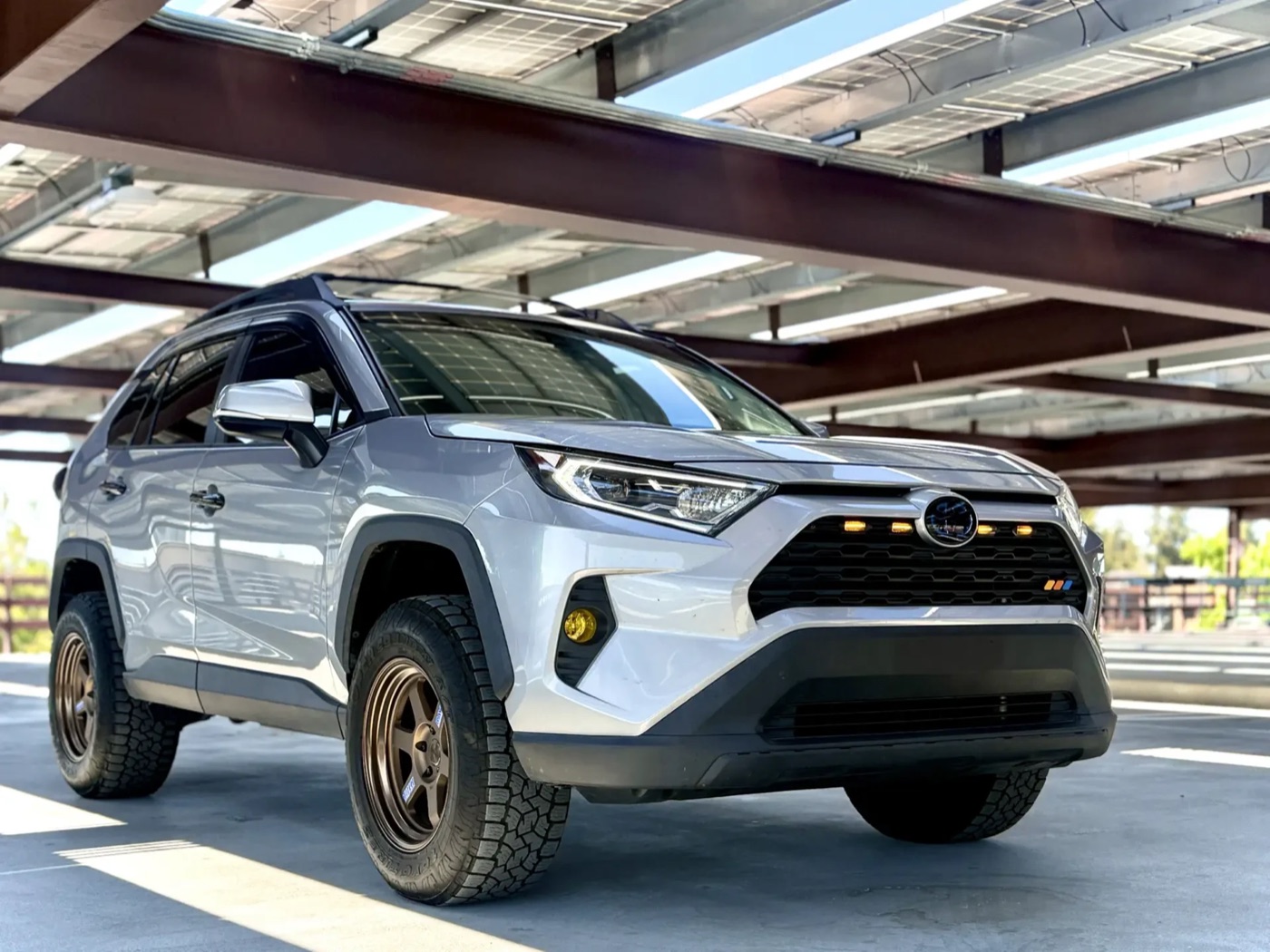 Front three-quarter view of the same white RAV4 on bronze wheels