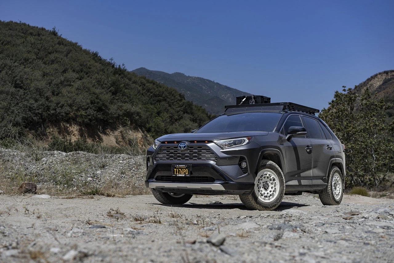 A Magnetic Gray 2021 RAV4 on white Black Rhino Fuji wheels and Falken Wildpeak A/T Trail tires with a roof rack and amber grille lights