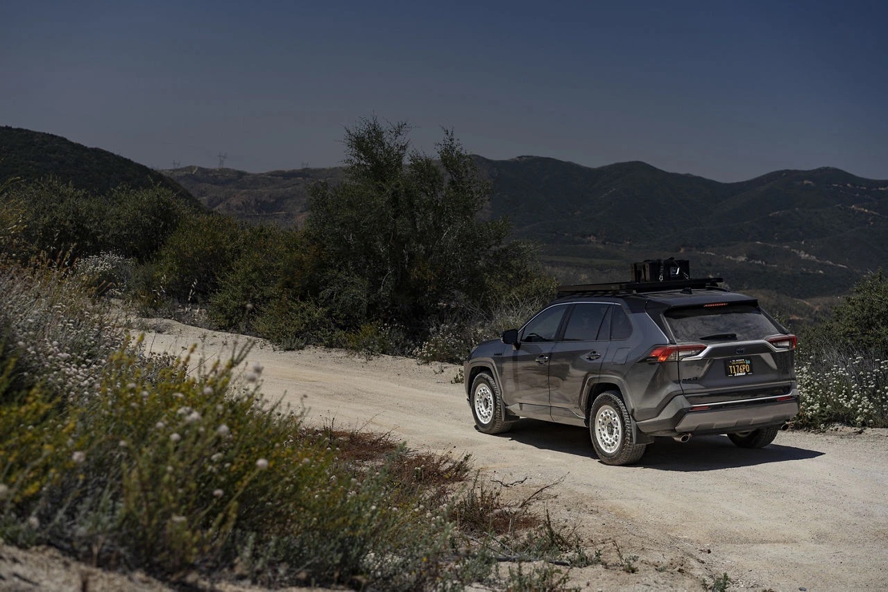Rear view of the gray RAV4 on white Fuji wheels on a dirt road