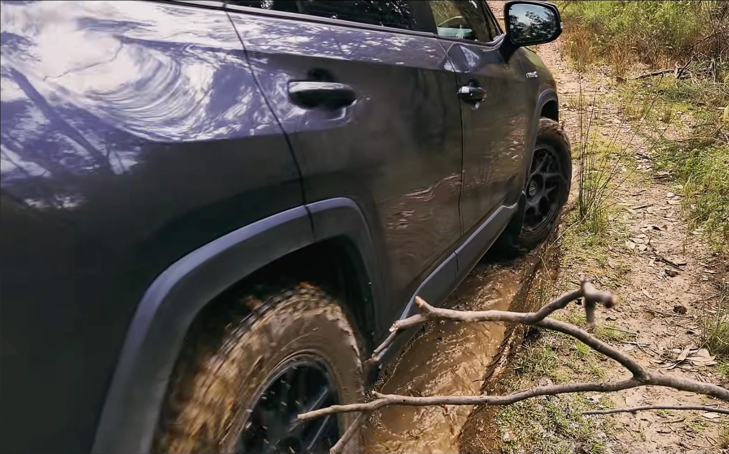 The same RAV4 Hybrid driving through a muddy, flooded rut