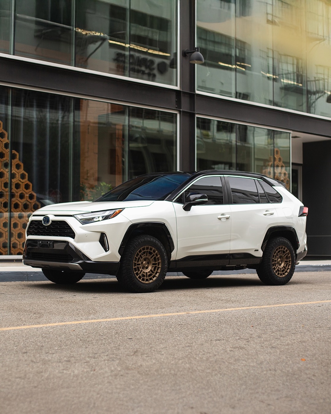 A white RAV4 Hybrid XSE with a black roof on satin bronze Fittipaldi FT109 wheels and Atturo all-terrain tires in 245/65R17