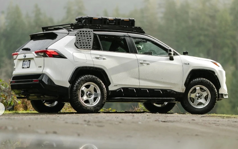 A white RAV4 Prime XSE on machined silver Black Rhino Sol wheels and Maxxis RAZR AT tires, with a roof rack and window panels