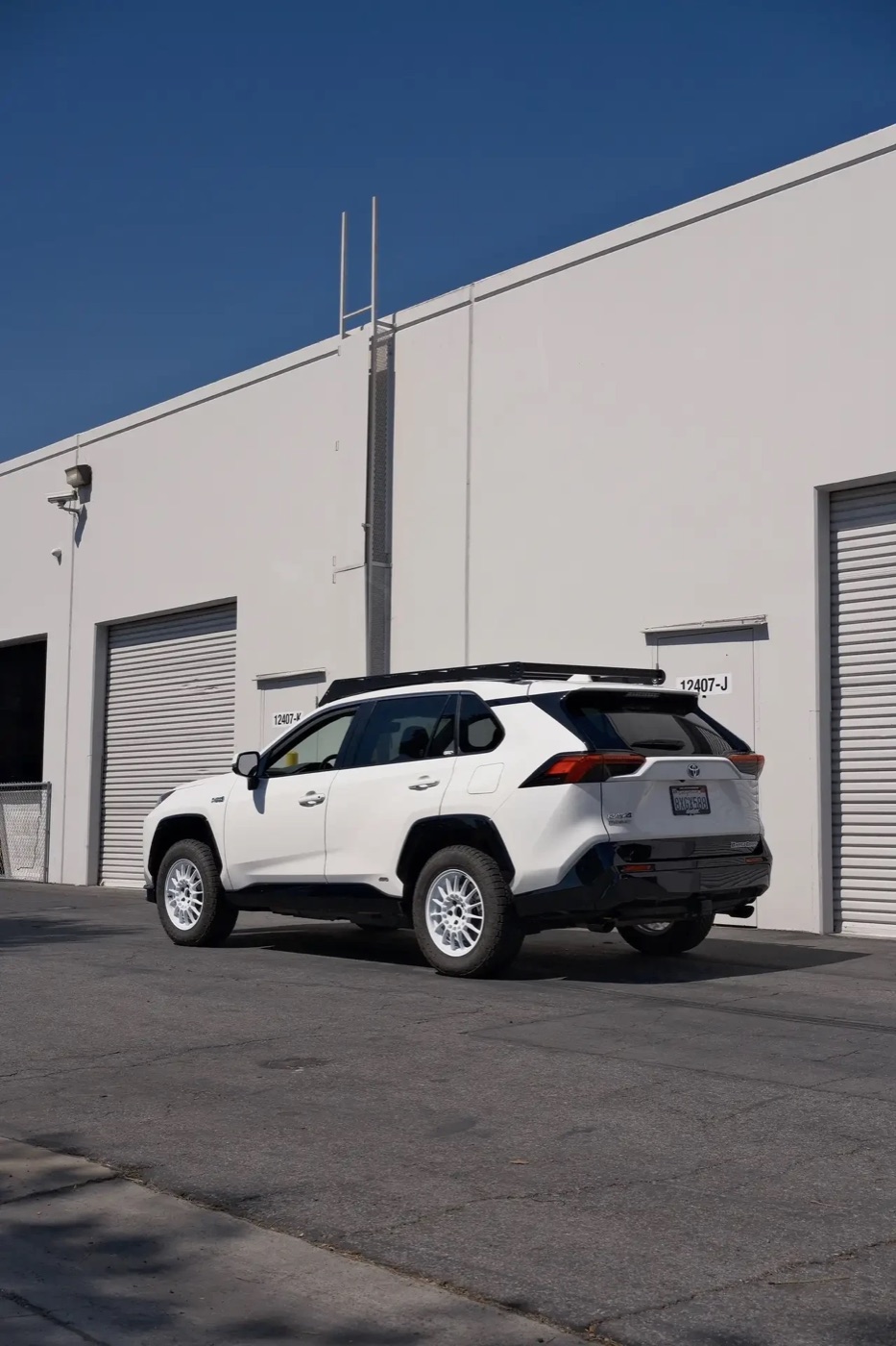 Rear three-quarter view of the white RAV4 Prime on white wheels