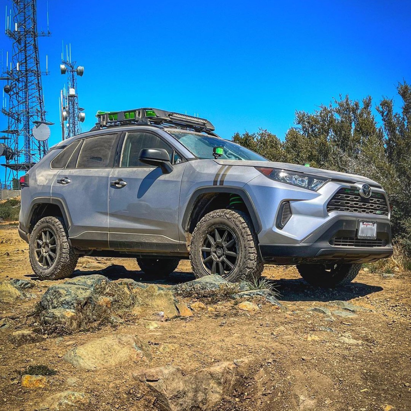 A gray RAV4 on matte black Voxx Monte wheels on rocky ground